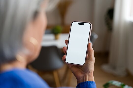 Hand holding a smartphone with blank screen at home
