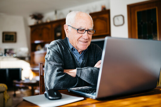Portrait of smiling senior man with laptop at home