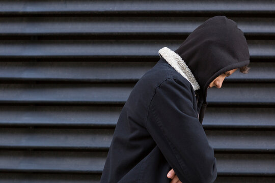 Lonely teenage boy in front of black background looking down