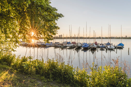 Germany, Hamburg, Sailboats moored along Outer Alster Lake jetty at sunrise