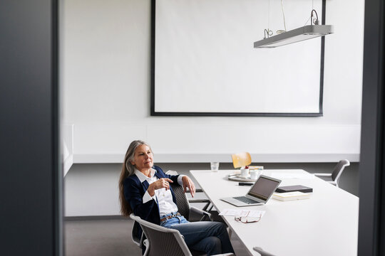 Senior businessswoman sitting at conference table with laptop