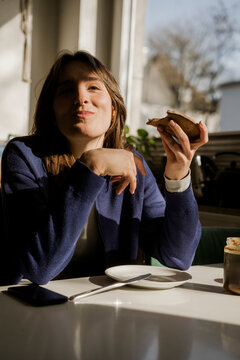 Smiling Gen Z woman eating bread for breakfast at home
