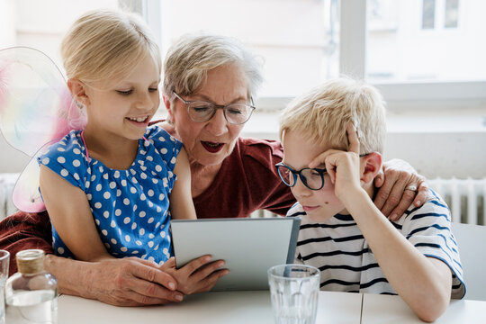 Grandmother and grandchild playing on a tablet indoors