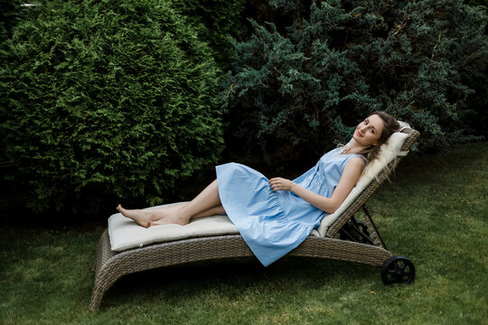 Woman relaxing on deck chair by plants in garden