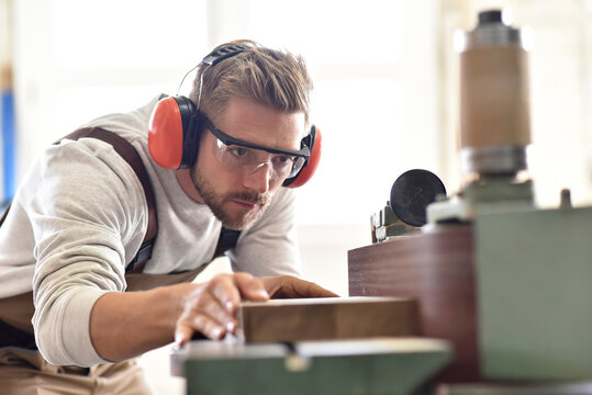 Carpenter using belt sander in his workshop