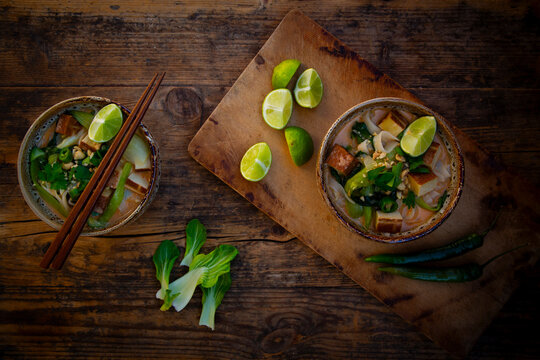 Thai curry soup with smoked tofu and rice noodle on wooden table