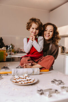 Portrait of happy mother and daughter with Christmas cookies in kitchen