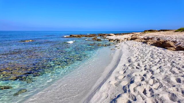 Is Arutas beach in Sardinia, Italy. Beautiful tropical-like coast with unique quartz white sand, crystal clear turquoise water and rocky shoreline under a clear blue sky