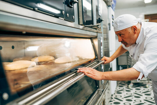 Working baker preparing the oven to make bread