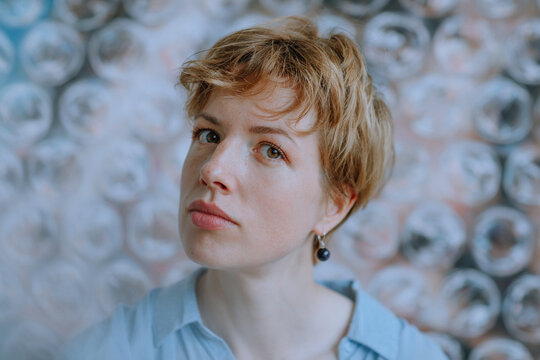 Thoughtful female artist against painting wrapped in bubble wrap