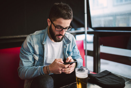 Young man text messaging in a pub