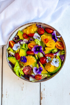 Bowl of mixed salad with avocado, tomatoes and edible flowers
