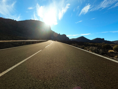 Scenic view of empty asphalt road amidst mountains on sunny day