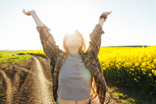 Woman raising arms on country road in spring