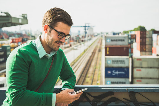Man at freight yard looking at cell phone