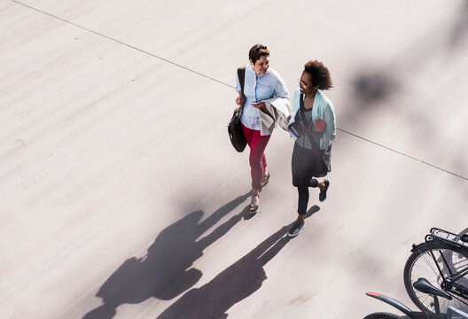Two businesswomen walking and talking, seen from above