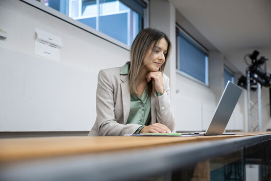 Businesswoman smiling at laptop during work in modern office