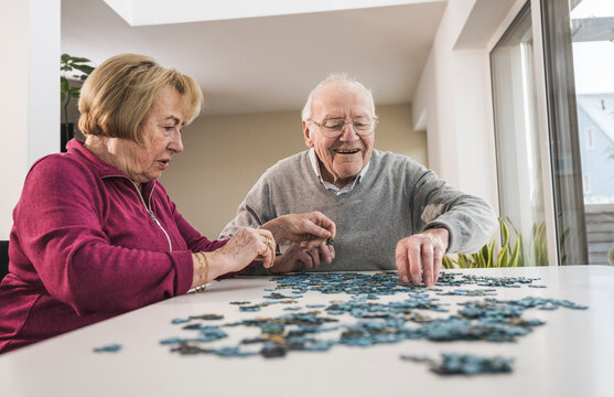 Happy man and woman playing puzzle game at home