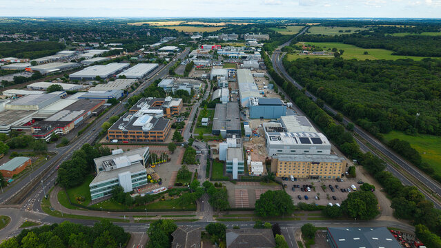 Aerial view of an industrial estate featuring various commercial buildings, warehouses, and office complexes surrounded by green spaces and roads in Stevenage, England, United Kingdom.
