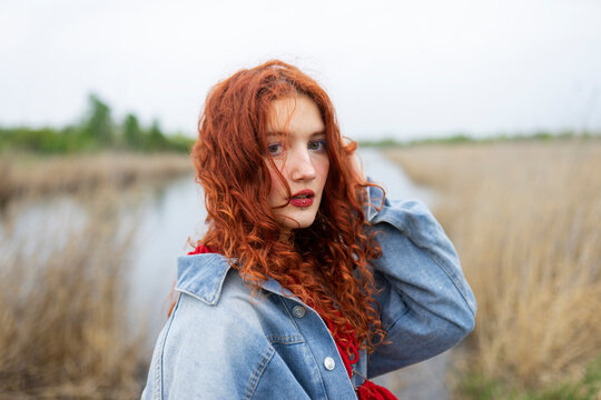 Woman with red hair in denim jacket outdoors in summer