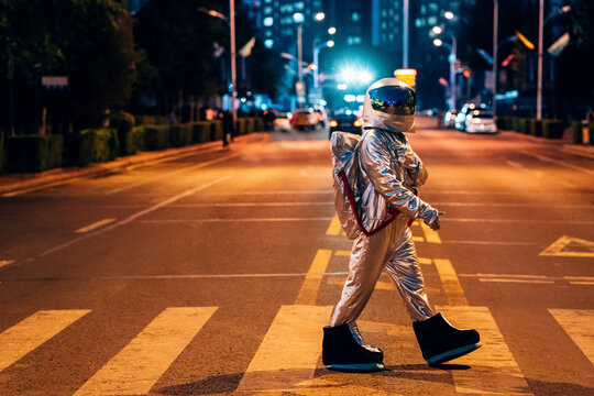Spaceman walking on a street in the city at night