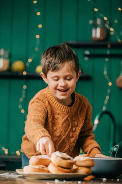 Happy boy with cinnamon buns in kitchen
