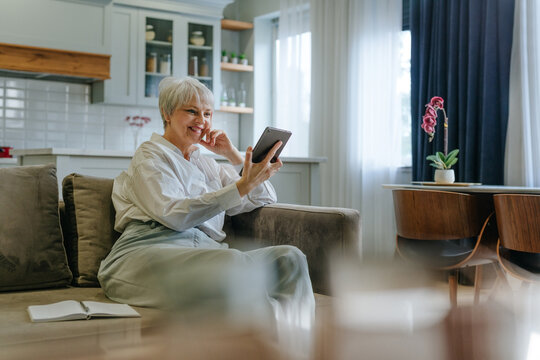Woman using a digital tablet while relaxing on a cozy sofa at home