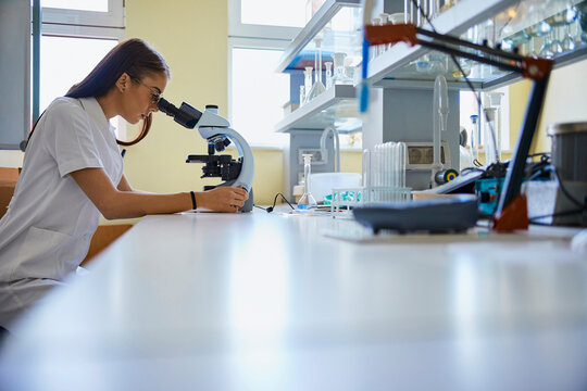 Young woman using microscope in laboratory