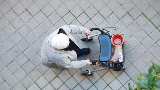 Anciana con caminador pelo blanco andador movilidad rollator persona mayor pasear tercera edad vieja manillar y ruedas desde arriba perspectiva a&eacute;rea cenital vista dron
