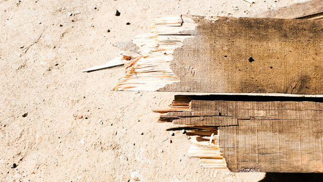 Damaged wooden beam with splintered end lying on construction site ground showing material wear and building demolition details