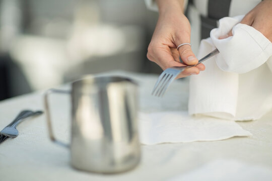 Close-up of waitress preparing dining table in restaurant