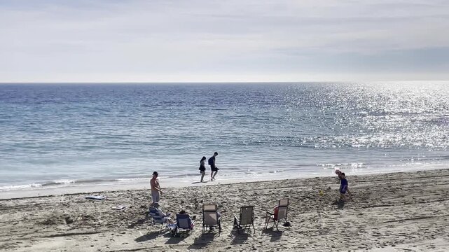 Familia y personas playa silla hamaca disfrutando de mar, sol y vacaciones de verano ni&ntilde;os jugando bal&oacute;n en arena y paseo orilla sonido de olas y marea beach summer and sun people playing ball