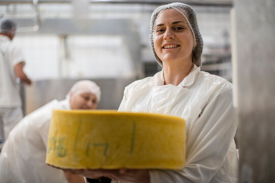 Cheese factory worker holding labeled cheese wheel