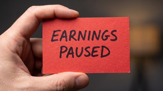Hand Holding Earnings Paused Handwritten Red Card Blur