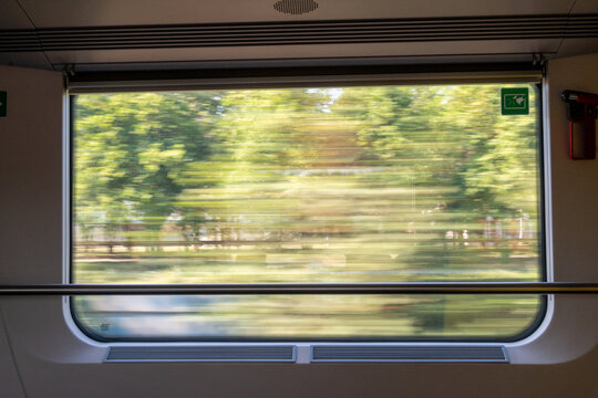 View from inside a moving passenger train with blurred green landscape visible through the window.