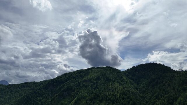Dramatic backlit storm cloud above a forested mountain ridge