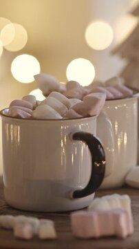 Mugs Of Hot Cocoa With Marshmallow Topping In A Christmas Decorated Kitchen With Blurred Garland Lights, Vertical Video