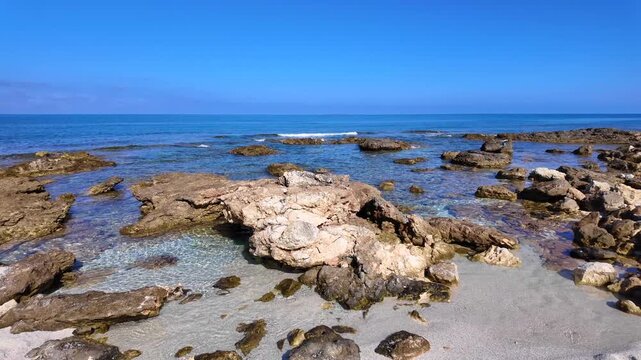  Rocky reef and crystal clear turquoise sea at Is Arutas beach in Sardinia, Italy. Scenic coastal landscape of mediterranean rocky shoreline under a blue sky