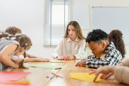 Teacher and diverse students doing arts and crafts in a classroom, Elementary school children and teacher working on creative paper project, Education concepts