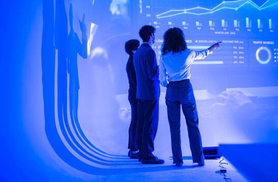 Business professionals reviewing business analytics and performance dashboards on a large digital display