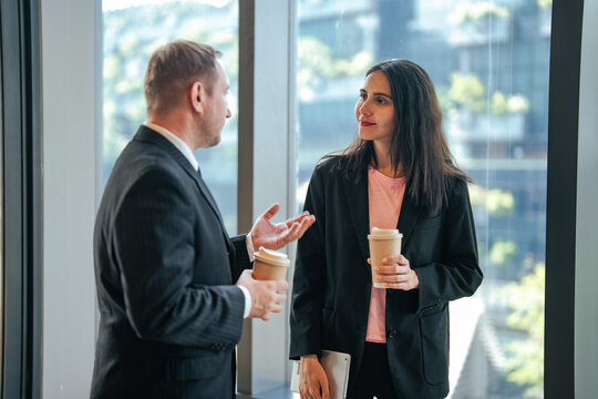 Business partners relaxing with coffee while exchanging ideas before executive meeting. Professional networking, workplace communication, leadership, consulting.