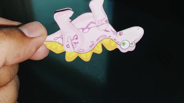 Hand Holding Cute Pink Stegosaurus Toy Close Up View