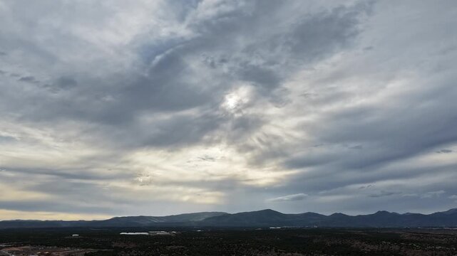 4K UHD drone timelapse: expansive southwest plateau scale grounds layered grey overcast skies. Dynamic weather shift captures piercing sunbeams and dense cloud formations for nature backgrounds.