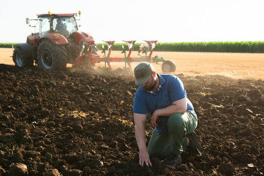 Young farmer on farmland with tractor in background
