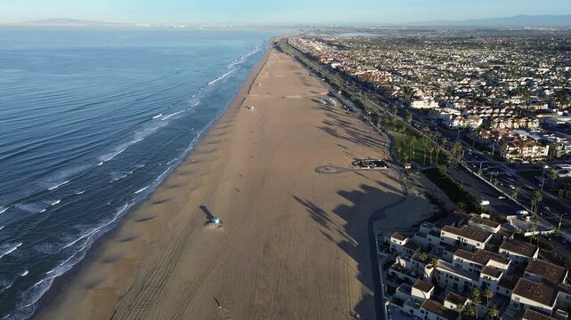 Shoreline Coastal Landscape shows wide Huntington Beach sands stretch alongside Pacific, flanked by residential blocks. Aerial views capture rhythmic ocean flow meets coastline, Orange County, CA