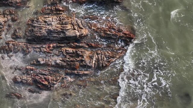 Layered rocks jut from ocean in aerial perspective