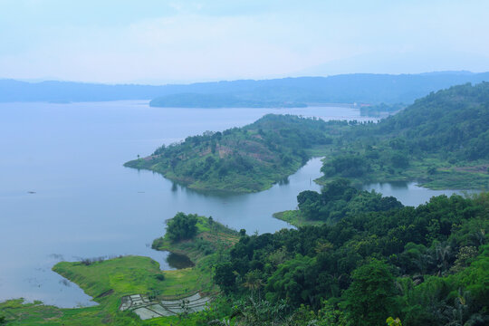 Aerial View Of Vast Reservoir Surrounded By Lush Forested Hills And Distant Mountains