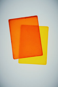 Overlapping transparent yellow and orange homemade glycerin soap bars on gray background
