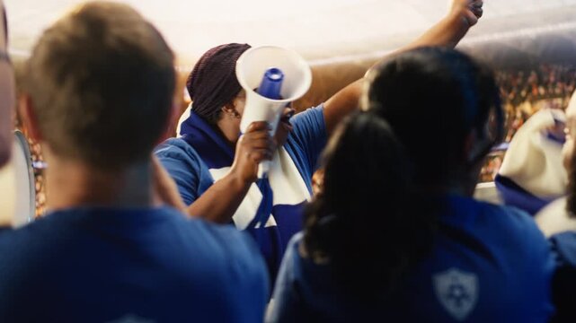 Enthusiastic woman in soccer stadium screaming in megaphone, encouraging players, showing female fan leader galvanizing large crowd in sports venue during match day for fan culture content.