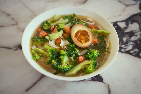 Close up of chicken broth with Ajitsuke Tamago (Japanese soft-boiled egg) and vegetables